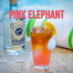 "Pink Elephant" cocktail on a table with ice cubes and a bottle of T3 Vodka in the background